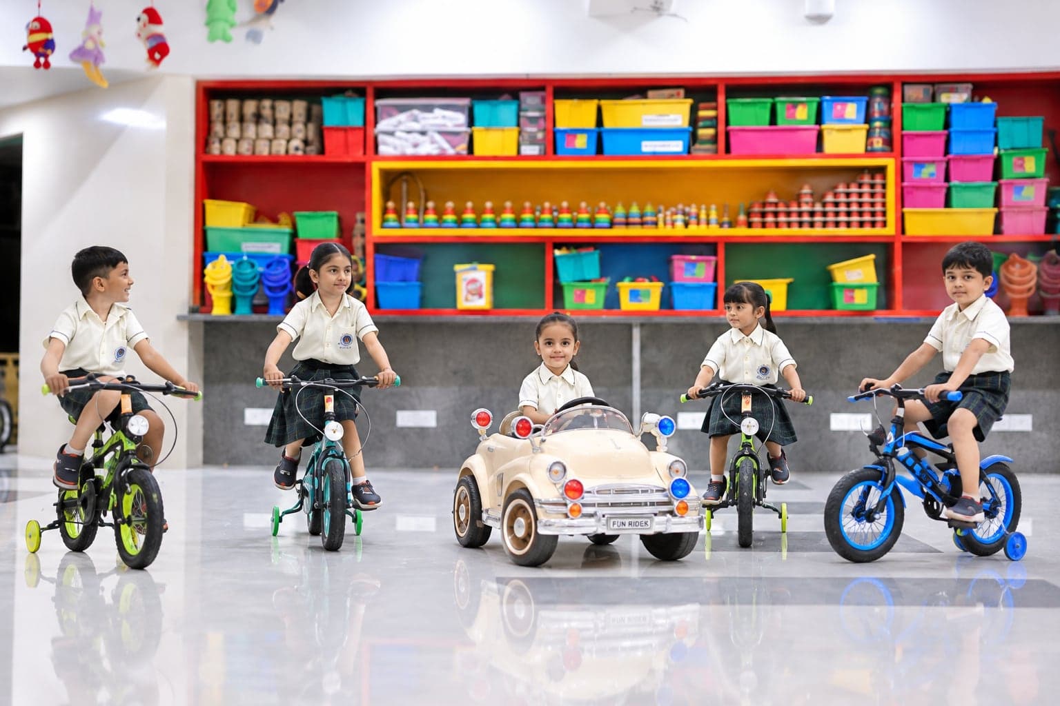 Primary children with bicycles and a toy car in the activity room