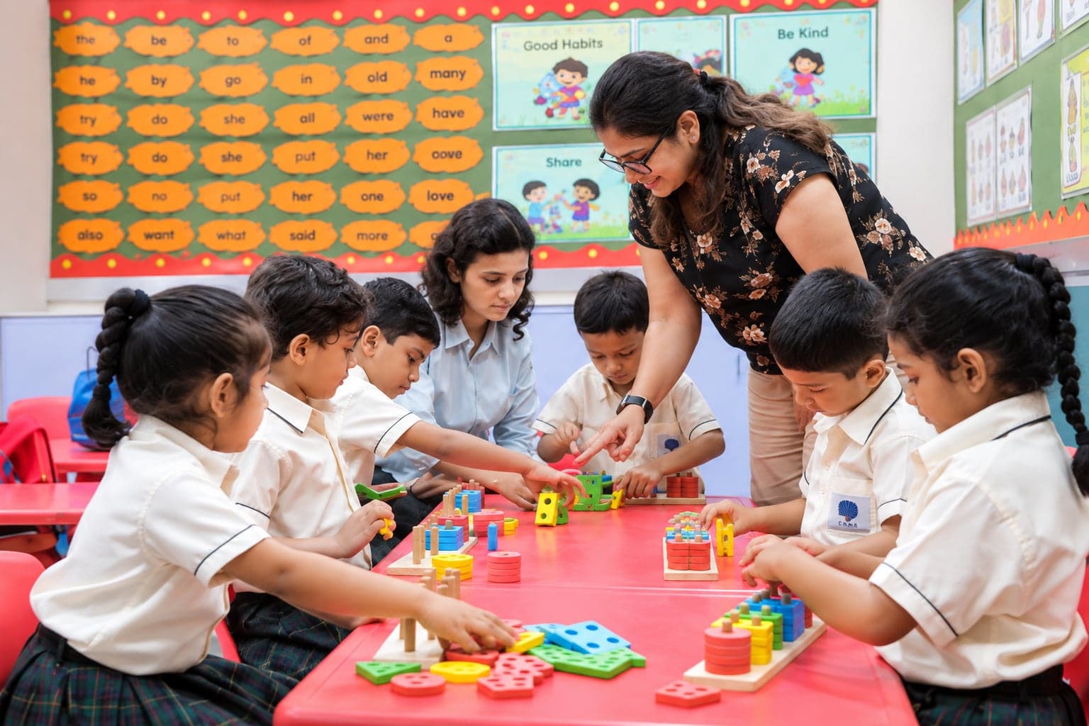 A teacher helping Primary children with a shape-sorting activity