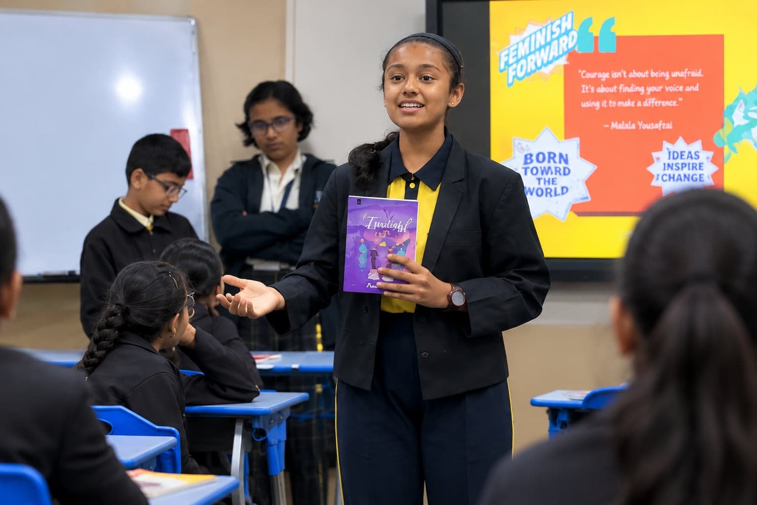 A student speaking to her class while holding a book
