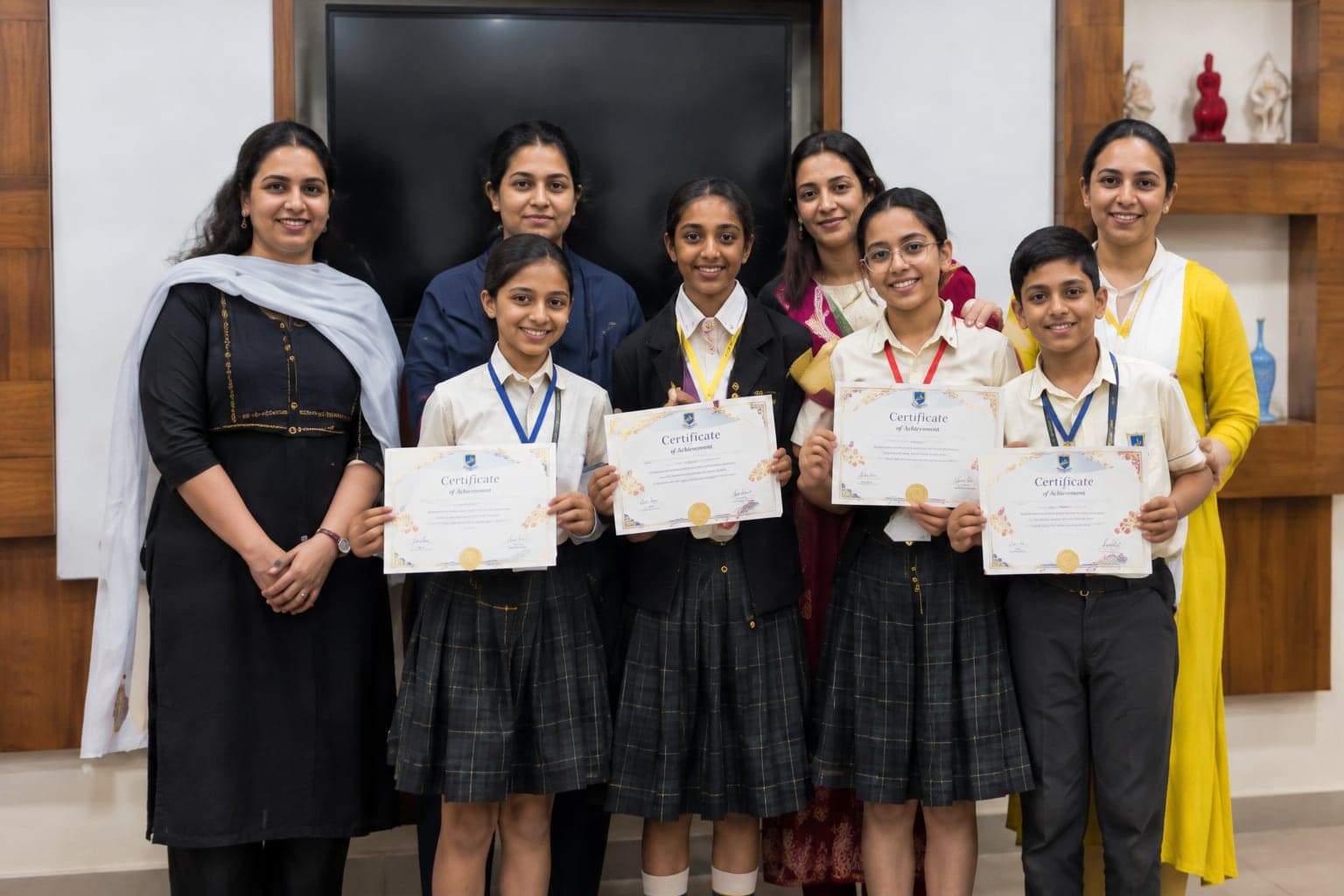 Students holding certificates with their teachers